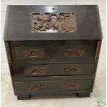A Mid Century hardwood bureau, heavily carved with far Eastern scenes (H106cm W92cm D43cm)