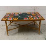 A Mid Century multi coloured tile topped table on bamboo legs (H43cm W89cm D45cm)
