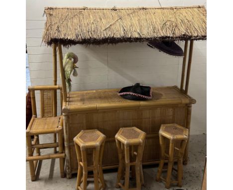 A Mid century bamboo Tiki bar with three stools and a chair. The sheltered bar features a fringed roof and concealed shelf. 