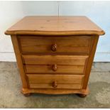 A pine three drawer bedside table on bun feet (H52cm W53cm D40cm)