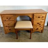 A pine kneehole dressing table flanked by six drawers on either side with cream upholstered stool (