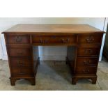 A brown leather topped pedestal desk, central long drawer flanked by four shorter (H76cm W120cm