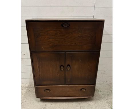 A dark Ercol bureau on castors, the fall opening to writing surface and storage with a two door cupboard and drawer under 