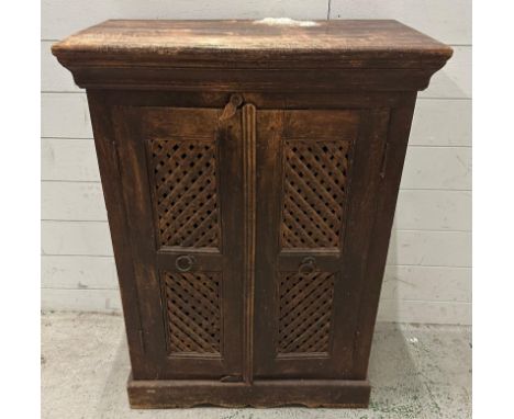 A teak maharani style two door cabinet, the colonial style lattice work front opening to a single shelf (H92cm W67cm D37cm)