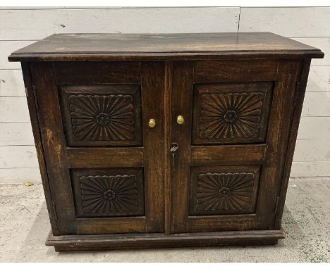 An Indian hardwood cabinet with florally carved panelled doors opening to a single shelf (H77cm W92cm D47cm)