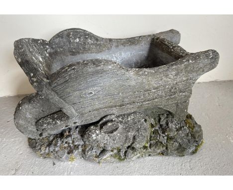 A concrete garden planter in the form of a wheelbarrow with rabbits. Approx. 29cm tall x 46cm long. 