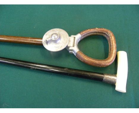 AN EBONY WALKING CANE WITH IVORY TAU HANDLE AND SILVER FERRULE, DATED 1903 AND A LEATHER HANDLED SHOOTING STICK 