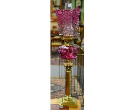 A Brass Corinthian Column Oil Lamp, cranberry shade and reservoir, stepped base, 77cm high