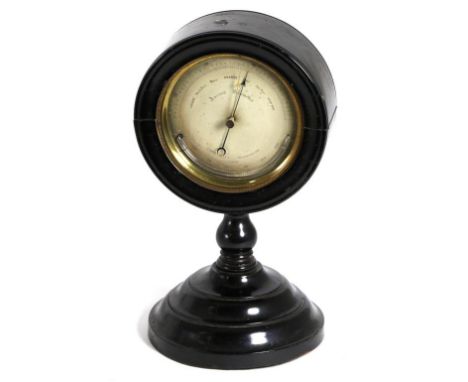 ^ An Ebonised Desk Aneroid Barometer, circa 1890, circular hinged top raised upon a turned base, silvered dial numbered 21299