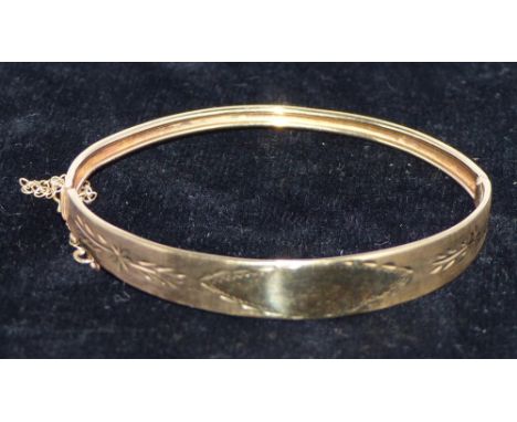 A yellow metal bangle with chased decoration, and safety chain, stamped '375', 6.6 gm