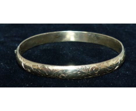 A 9 carat hallmarked gold bangle with chased decoration, 9.6 gm
