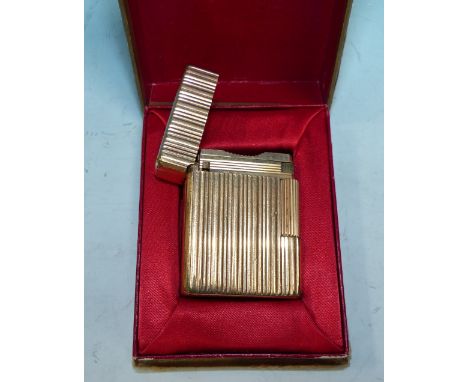 A gilt metal cigarette lighter by S T Dupont, in original box with booklet; a 1930's carved oak aneroid barometer and thermom