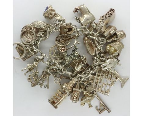 Hallmarked silver charm bracelet with twenty eight charms and hallmarked silver padlock clasp, L: 18 cm, overall 94g. P&amp;P
