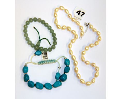A single strand necklace of fresh water pearls together with a jade bracelet and a turquoise bracelet.