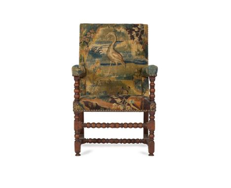 A WALNUT AND VERDURE TAPESTRY UPHOLSTERED ARMCHAIR  18TH CENTURY With bobbin turned supports throughout, the raised back cent