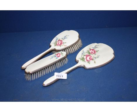 A pretty enamel hand mirror and two brushes from a dressing table set