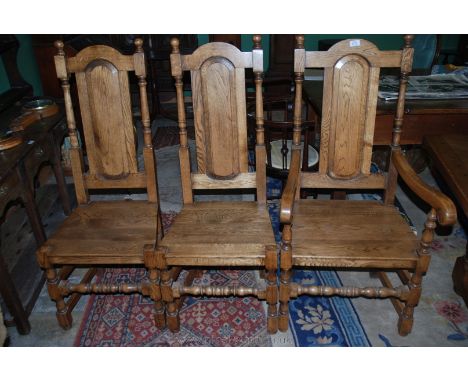 A set of eight solid Oak baronial style Dining Chairs (including two carvers) having oval raised and fielded panel backs, in 