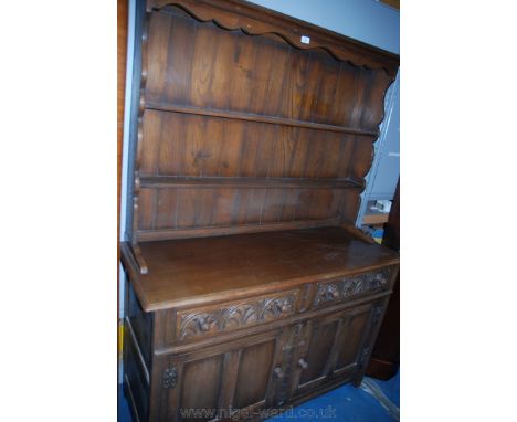 A reproduction Oak Priory style Dresser, having moulded cornice to the two rebated shelf plate rack with fret cut sides, over