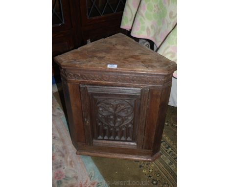 An antique Corner Cabinet of small proportions, moulded cornice over carved frieze, single panel door with ornate Gothic styl