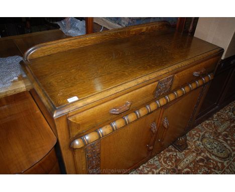 A 1920's Oak Sideboard, having moulded upstand back, moulded edge top over two shaped front frieze drawers separated by carve