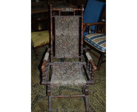 An American Rocking Chair, circa 1880, of turned Oak spindle construction with nailed floral pattern carpet style fabric back