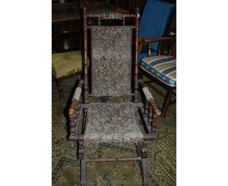 An American Rocking Chair, circa 1880, of turned Oak spindle construction with nailed floral pattern carpet style fabric back