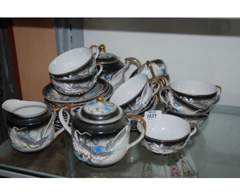 A black ground Japanese Teaset with a Geisha lithograph to the base of the cups, some chips and cracks.