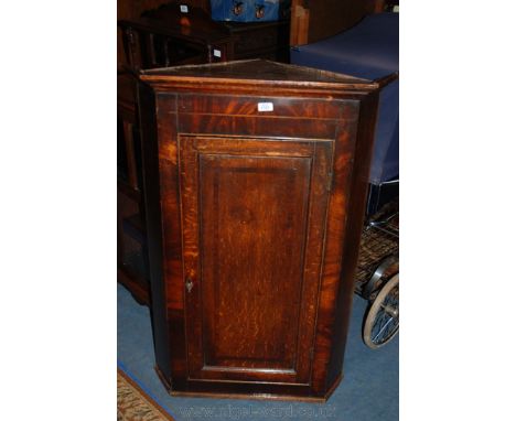 A Georgian Oak and Mahogany wall hanging single cross-banded panel doored Corner Cabinet