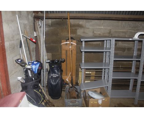 A box containing various vintage tool heads, radiator valves, oil can and a wooden handled pitch fork