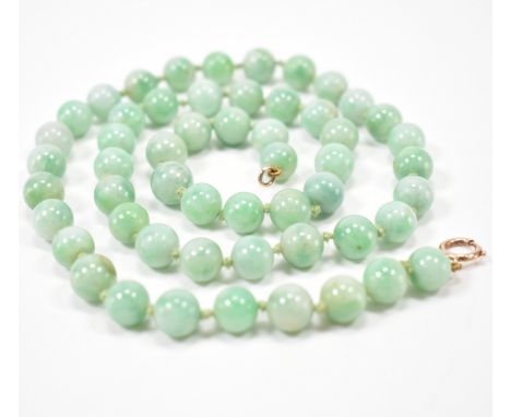 A vintage 20th Century jade and gold beaded necklace. The necklace having round green jade beads on a knotted string with a g
