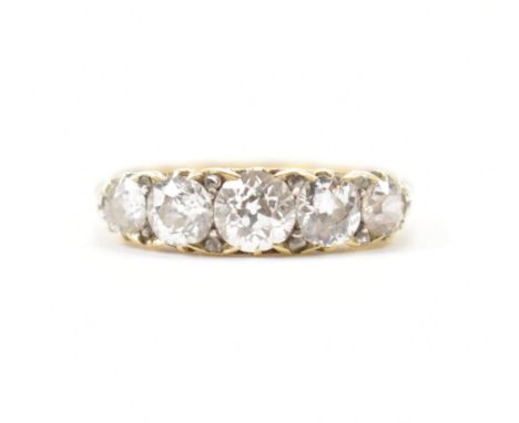 A gold and diamond five stone ring. The ring set with five graduating old cut diamonds to scrolled gallery and plain band. Es