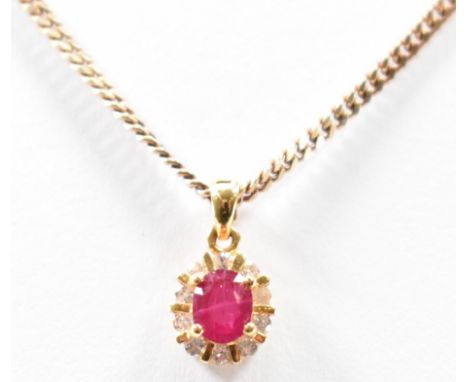 A gold, ruby and diamond pendant necklace. The hallmarked 18ct gold pendant set with an oval cut ruby with a halo of round cu