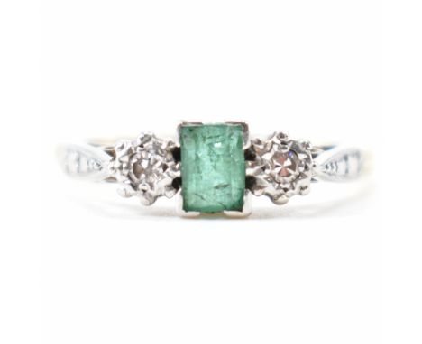 A 1930s 18ct gold emerald and diamond three stone ring. The ring being set with a step cut emerald flanked by two round singl