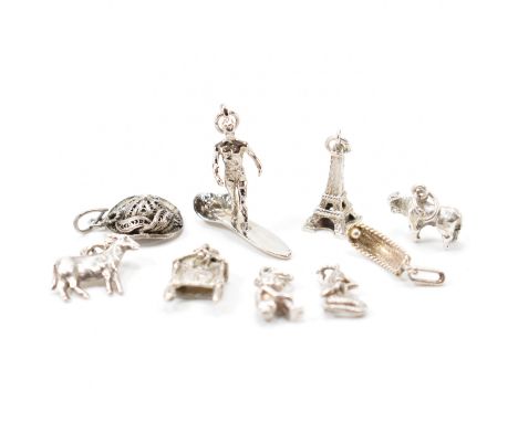 A group of vintage silver white metal bracelet charms. The lot to include a pixie, mermaid, Eiffel tower, cow, filigree hat a