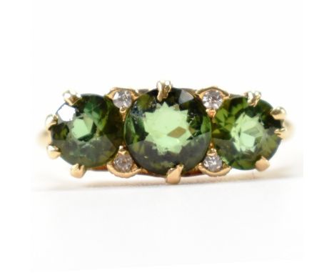 An 18ct gold tourmaline and diamond ring. The ring being set with three round mixed cut tourmalines with four diamond accent 
