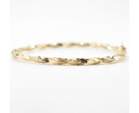A gold twist bangle bracelet having brushed gold with a tongue and groove clasp. Marked 375. Measures 61mm x 52mm. Total weig