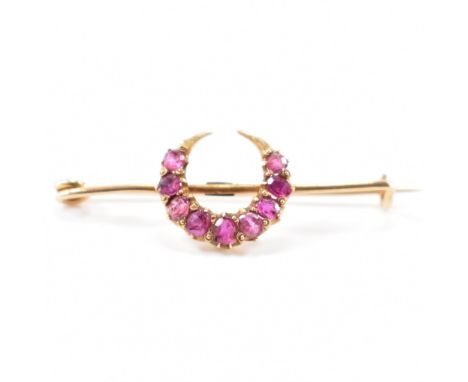A 19th Century Victorian 18ct gold and ruby crescent brooch. The brooch of safety pin form set with nine graduating round cut