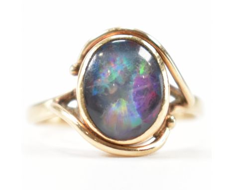 A gold and simulated opal crossover ring. The ring having a central oval simulated opal cabochon within a crossover setting. 