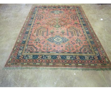 A Turkey style Carpet, multi-bordered and decorated stylised motifs on a pale red ground, 12ft x 8ft 9in