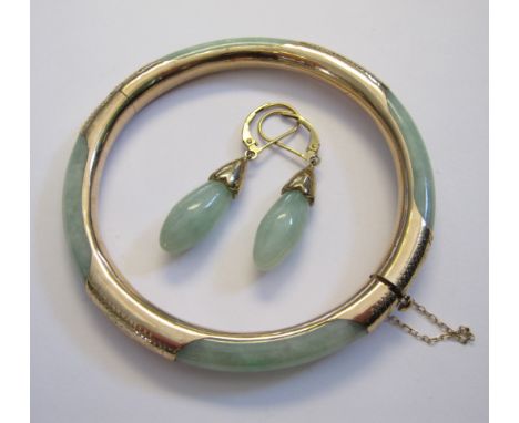 A Jade hinged Bangle with engraved 9ct gold mounts and pair of Jade drop Earrings on 9ct gold fittings