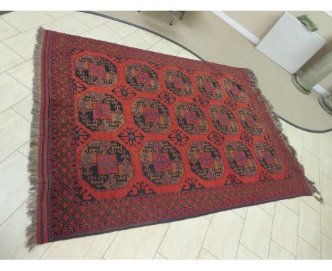 A bordered Afghan Carpet with three rows of five large guls on a brick red ground, 9ft 6in x 6ft 9in