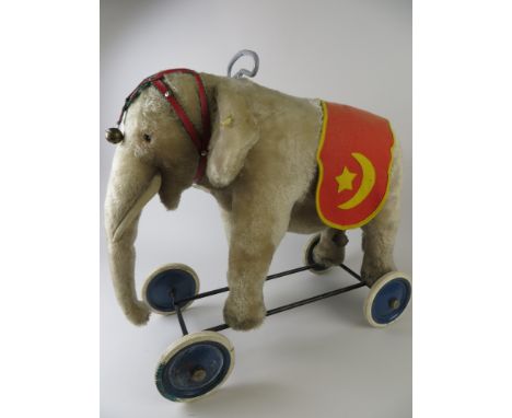A Steiff Elephant on wheels with original blanket and trappings. Button in ear and yellow label also an Original Steiff label