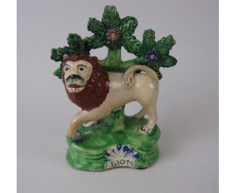 A Staffordshire standing Figure of Lion with bocage tree trunk support, the shaped base titled  Lion , 5in H