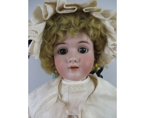 A large bisque headed Handwerk Doll with large brown eyes and pierced ears. Fully jointed body. Ornate cream silk costume and