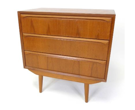 A 1960s Danish teak low chest of three long drawers, having curved integral elongated handles, raised on turned slightly tape