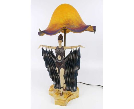 After Chiparus - a painted resin table lamp, having a mottled orange and blue glass domed and wavy rimmed shade, the standing