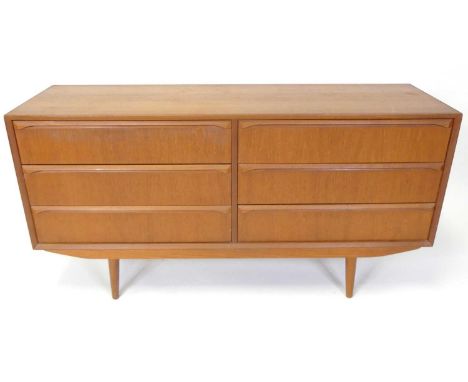 A 1960s Danish teak compact sideboard, having twin flights of three long drawers, each with curved integral elongated handles