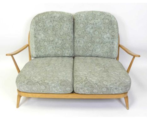 An Ercol blond beech stickback two-seater Windsor sofa, having slightly pronounced arm rests, webbed seat, and raised on turn