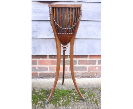An Edwardian jardiniere stand, decorated swags, on tripod splay supports