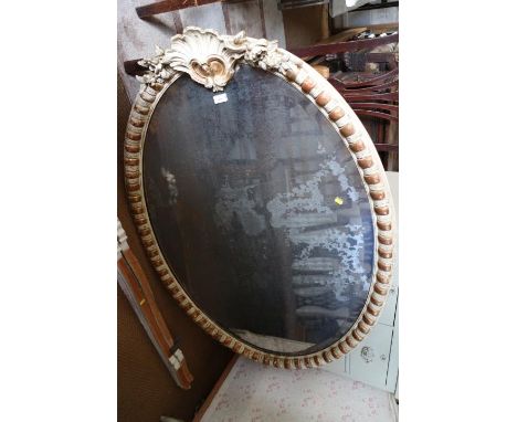 An oval wall mirror with scroll crest and moulded frame, bevelled plate 48" x 33 1/2"